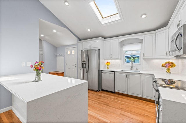 97 Great Western Rd, Harwich, MA 02645 - kitchen featuring a sink, light wood-style flooring, stainless steel appliances, a peninsula, and lofted ceiling with skylight