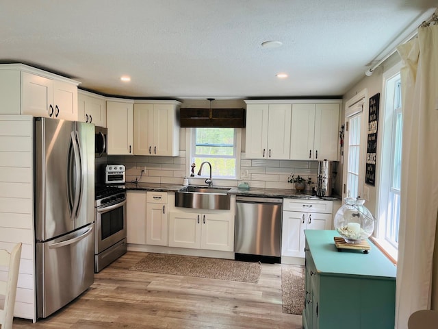 19 Artisan Way, Forestdale, MA 02644 - kitchen featuring dark countertops, a sink, light wood-style floors, stainless steel appliances, and tasteful backsplash