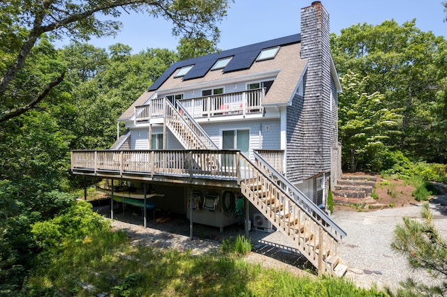 rear view of property featuring a deck and solar panels