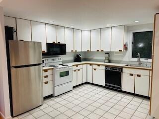 kitchen with sink, white cabinetry, light tile patterned floors, and black appliances