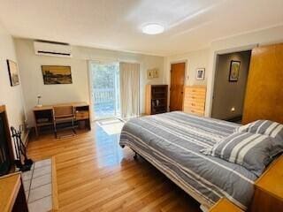 bedroom featuring access to exterior, wood-type flooring, and a wall mounted air conditioner