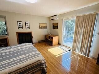 bedroom featuring light wood-type flooring, access to exterior, and a wall unit AC