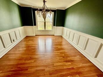 53 White Cliff Dr, Cedarville, MA 02360 - unfurnished dining area with crown molding, a chandelier, wainscoting, a decorative wall, and wood finished floors
