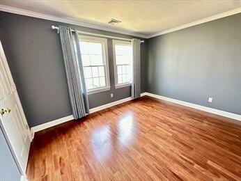 empty room with crown molding, baseboards, and wood finished floors