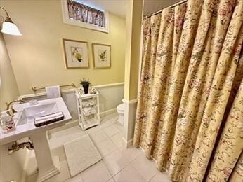 bathroom featuring tile patterned flooring, curtained shower, and toilet