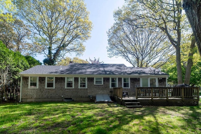 back of property featuring a wooden deck, a lawn, roof with shingles, and a chimney
