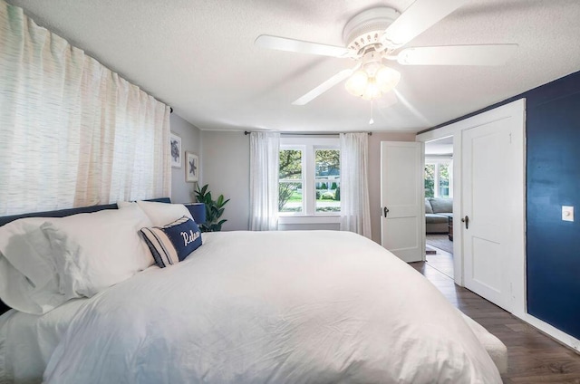 bedroom featuring wood finished floors, a textured ceiling, a ceiling fan, and baseboards