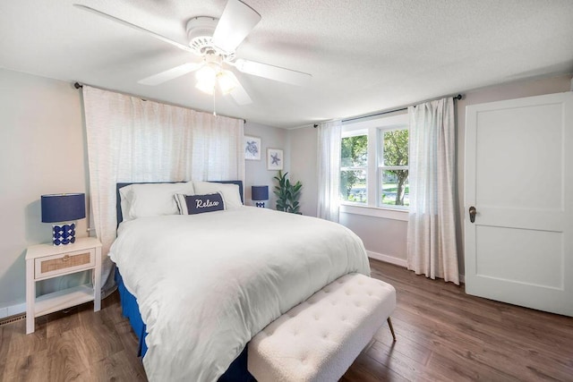 bedroom featuring dark wood-style floors, baseboards, ceiling fan, and a textured ceiling