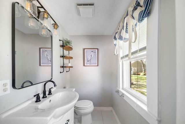 half bathroom with tile patterned floors, toilet, baseboards, and vanity