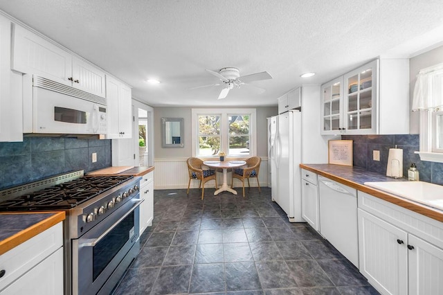 kitchen featuring white appliances, white cabinetry, glass insert cabinets, ceiling fan, and decorative backsplash