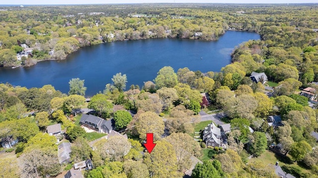 aerial view of property and surrounding area with a forest and a nearby body of water