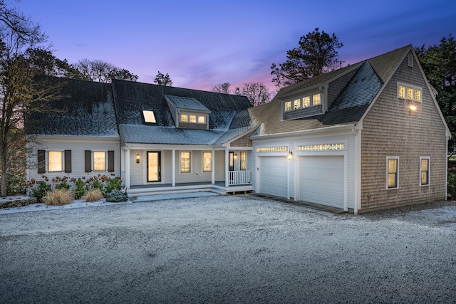 cape cod-style house featuring a garage and a porch