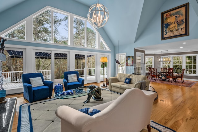 living room featuring an inviting chandelier, high vaulted ceiling, and light wood-type flooring