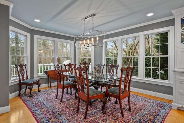 dining space featuring crown molding, an inviting chandelier, and light hardwood / wood-style flooring