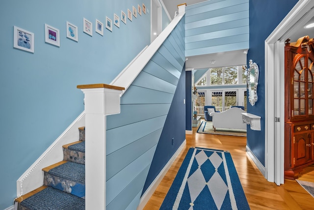 stairs featuring wood-type flooring and a towering ceiling