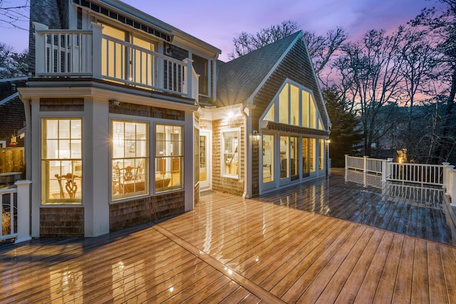 deck at dusk featuring a sunroom