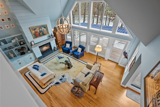 living room with a notable chandelier, high vaulted ceiling, and light wood-type flooring