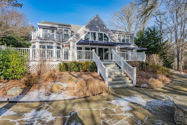 rear view of house featuring a balcony and a deck