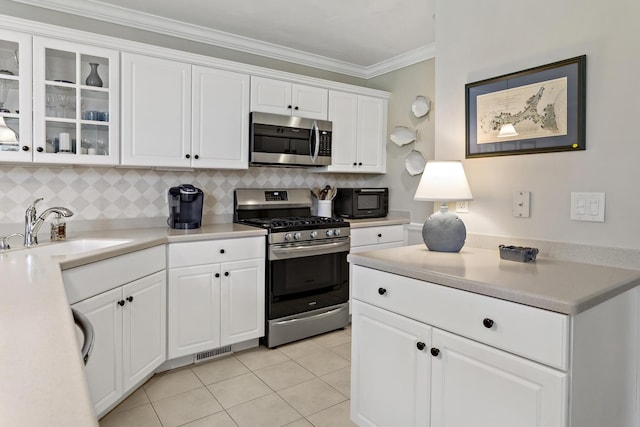 9 Sea Knoll Ct, Bourne, MA 02532 - kitchen with stainless steel appliances, white cabinets, decorative backsplash, light countertops, and crown molding