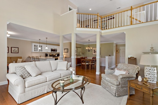 9 Sea Knoll Ct, Bourne, MA 02532 - living area with a high ceiling, wood finished floors, a chandelier, wainscoting, and crown molding