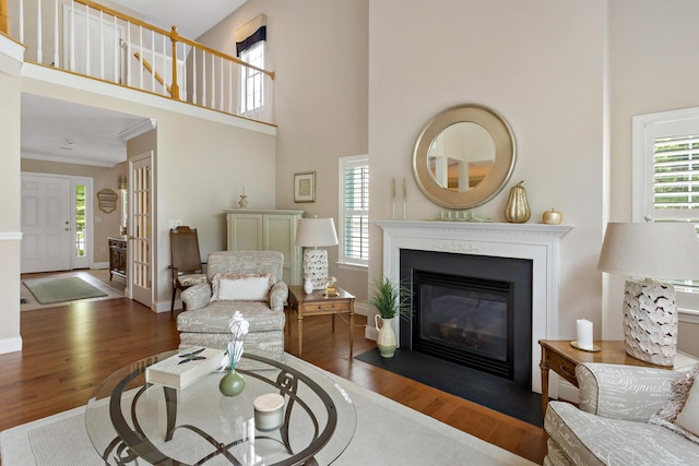 9 Sea Knoll Ct, Bourne, MA 02532 - living room featuring wood finished floors, healthy amount of natural light, a fireplace with flush hearth, a towering ceiling, and ornamental molding
