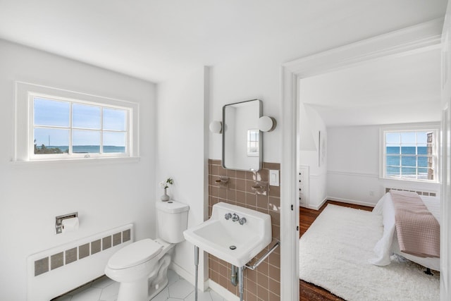 bathroom with toilet, a healthy amount of sunlight, radiator heating unit, and a sink