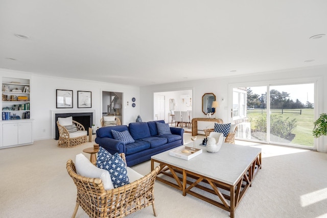 living area featuring ornamental molding, light carpet, a fireplace, and built in features