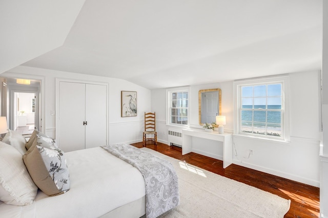 bedroom with radiator, a closet, dark wood-type flooring, baseboards, and vaulted ceiling
