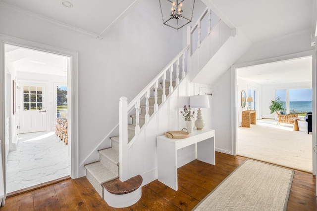 entrance foyer with a notable chandelier, crown molding, stairway, and hardwood / wood-style flooring
