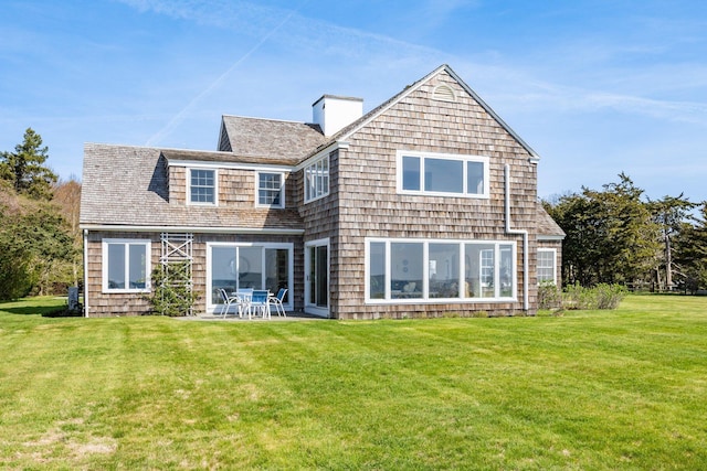 rear view of house featuring a patio area, a chimney, and a lawn