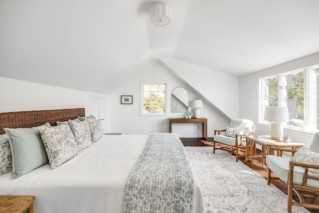 bedroom featuring lofted ceiling, multiple windows, and wood finished floors