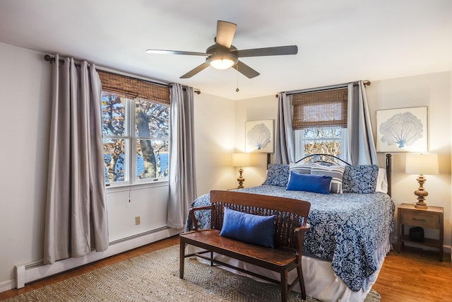 bedroom with a baseboard radiator, wood finished floors, and multiple windows