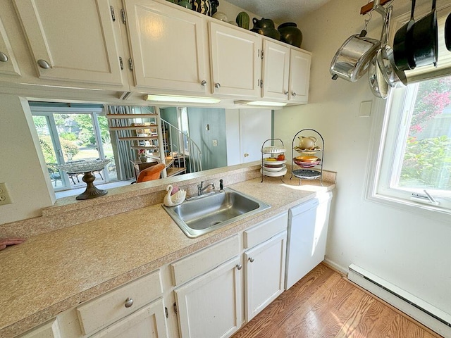 kitchen with sink, white cabinets, a baseboard heating unit, and light hardwood / wood-style floors