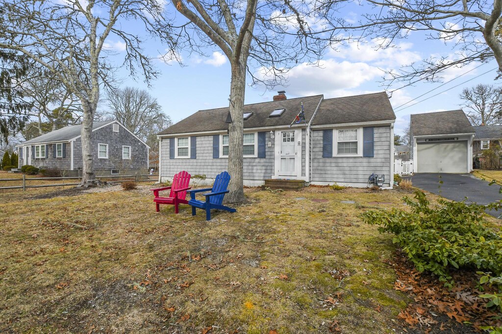 16 Indian Pond Rd, West Dennis, MA 02670 - view of front of house with fence, a chimney, entry steps, an outdoor structure, and a garage