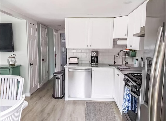 31 Northern Ave, Dennis Port, MA 02639 - kitchen featuring appliances with stainless steel finishes, a sink, light wood-type flooring, and wall chimney exhaust hood