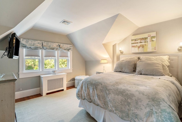 bedroom with wood-type flooring, radiator, and vaulted ceiling