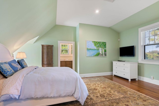 bedroom with connected bathroom, dark wood-type flooring, and lofted ceiling