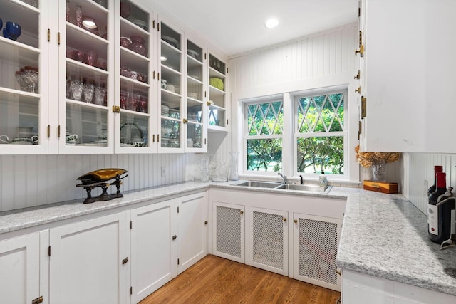 kitchen featuring sink, light stone countertops, white cabinets, and light hardwood / wood-style floors