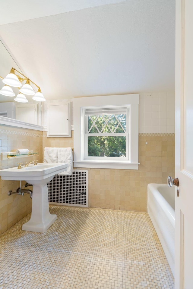 bathroom featuring a bath, tile patterned floors, and tile walls