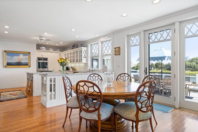 dining space featuring light wood-type flooring, plenty of natural light, and sink