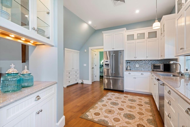 kitchen featuring light stone counters, white cabinetry, stainless steel appliances, and hanging light fixtures