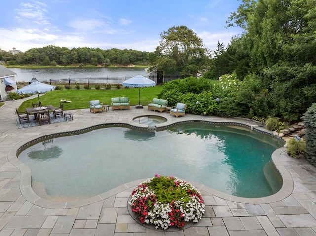 view of swimming pool with an in ground hot tub, a water view, a yard, and a patio area