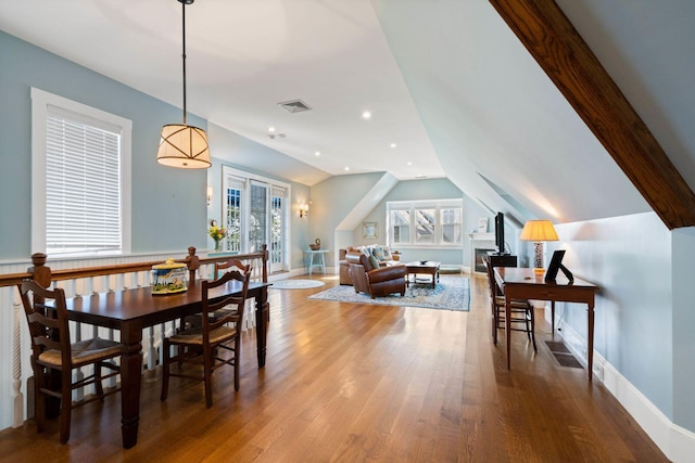 dining space featuring hardwood / wood-style flooring, vaulted ceiling, and a healthy amount of sunlight