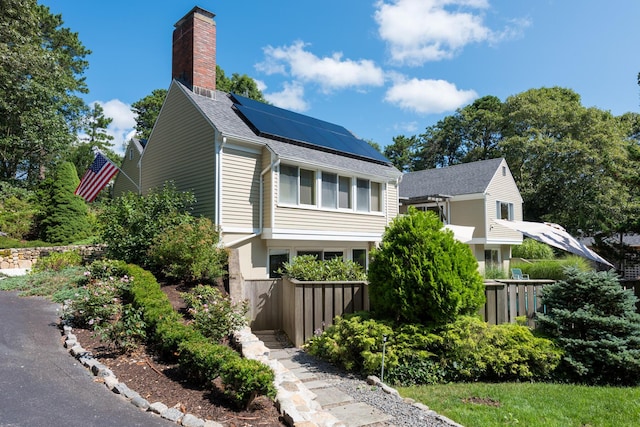 139 Prince Ave, Marstons Mills, MA 02648 - view of side of property with roof mounted solar panels, a chimney, and a shingled roof