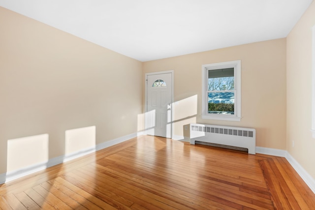 unfurnished living room with wood-type flooring and radiator heating unit