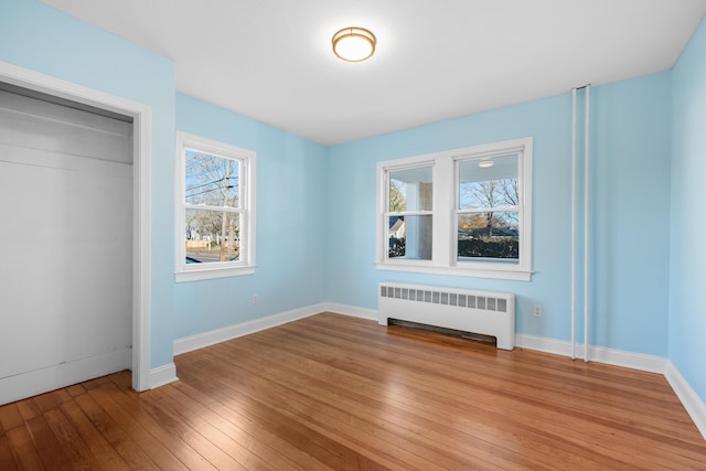 unfurnished bedroom with a closet, light wood-type flooring, and radiator