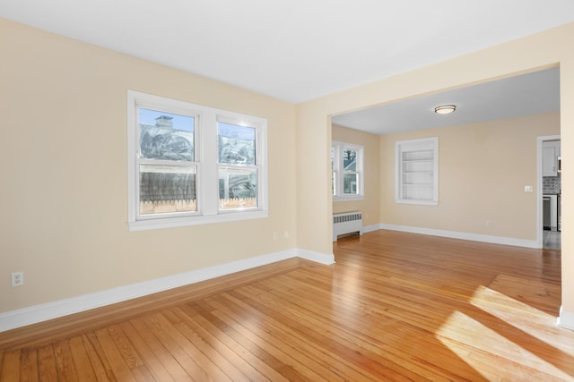 unfurnished living room featuring light hardwood / wood-style floors, plenty of natural light, and radiator heating unit