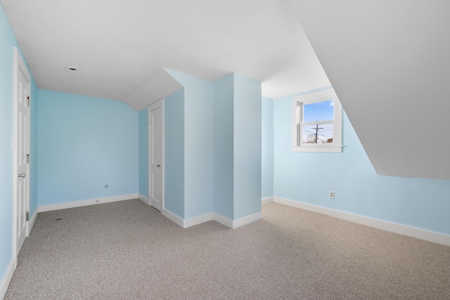 additional living space featuring light carpet and vaulted ceiling