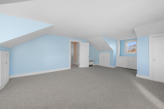 additional living space with radiator heating unit, lofted ceiling, and carpet flooring