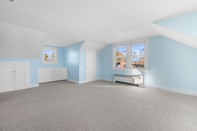 additional living space with light carpet, radiator, and lofted ceiling